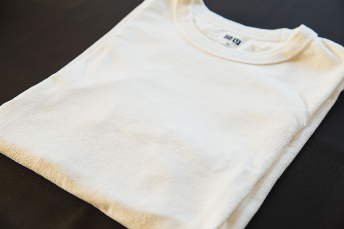 Folded cream tee showing the neck label and stitching